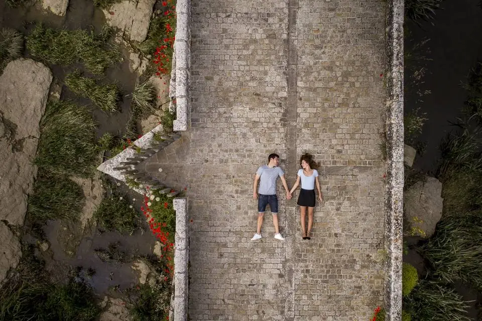 Pareja tumbada sobre un puente de piedra vista con dron en una sesión de preboda de Josu Izarra