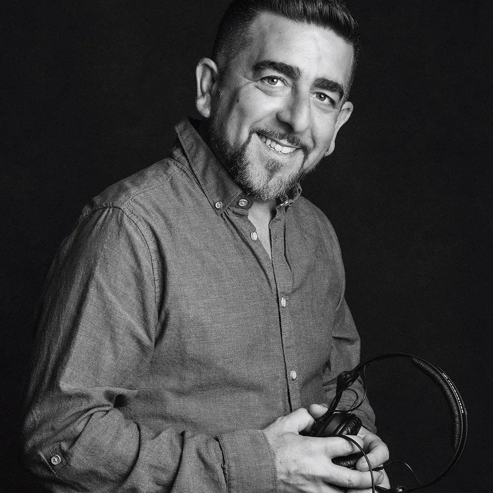 Retrato de estudio en blanco y negro de un hombre sonriente con auriculares, por Josu Izarra