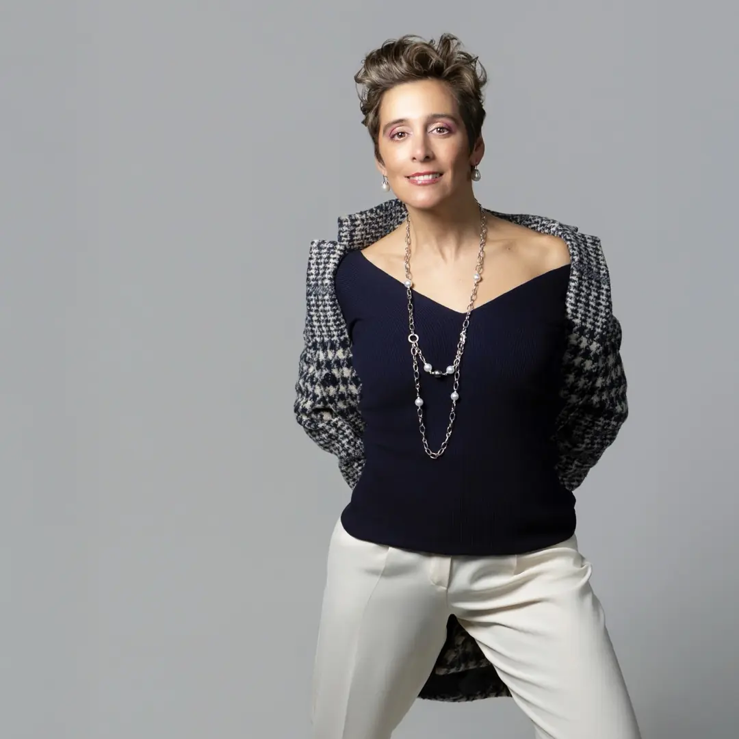 Retrato de moda en estudio de una mujer con chaqueta de pata de gallo sobre fondo gris, por Josu Izarra